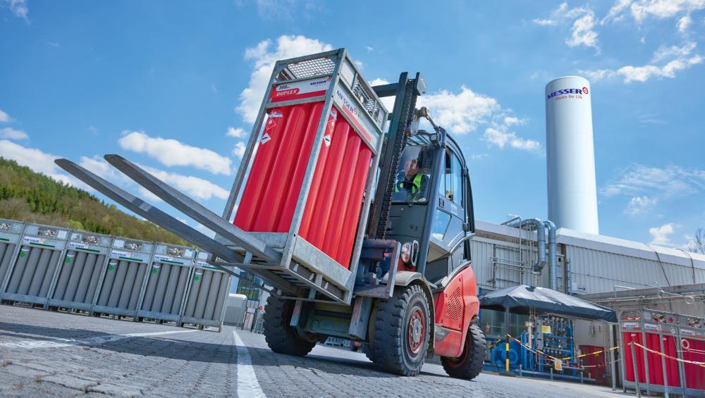 Hidrogén gázpalack-köteg mozgatása targoncával ipari környezetben a Messer telephelyén.